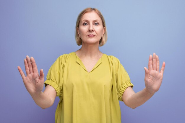 S blonde woman in yellow tshirt showing stop gesture