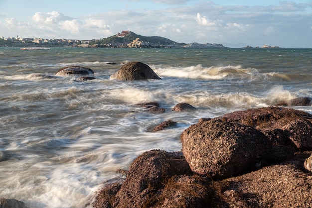 's Morgens schijnt de zon op de rotsen en golven op het strand;