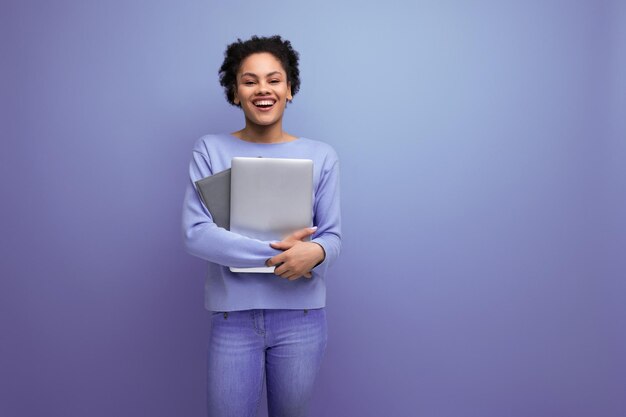 Photo s young afro hair brunette woman with laptop to work on blue background