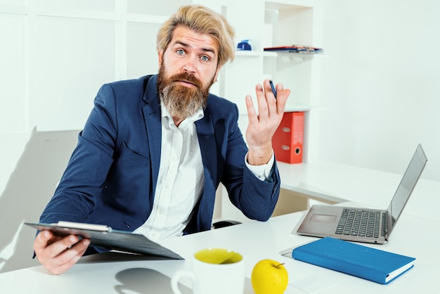 Saai baanportret van een jonge man die aan zijn bureau zit op kantoor, een grappige werker groothoek