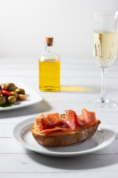 Photo sabor a tradicion tapa de jamon iberico dressed olives and a glass of white wine