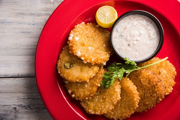 Sabudana Or Sago Vada is a traditional deep fried snack from India. Served with spicy green or peanut chutney. Serve  in wooden plate over colourful or wood background. Selective focus