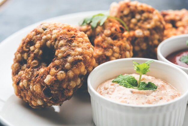 Sabudana vada of Sago gebakken cake geserveerd met pindachutney over humeurige achtergrond, populair vastenrecept uit India.