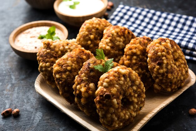 Sabudana vada 또는 Sago 튀김 케이크는 인도에서 인기 있는 단식 레시피인 변덕스러운 배경 위에 땅콩 처트니와 함께 제공됩니다.