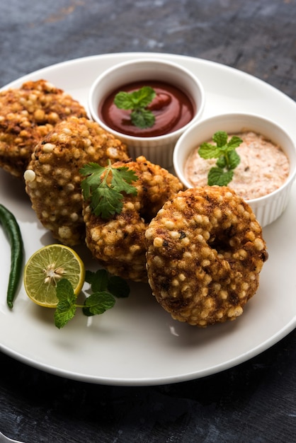 Sabudana vada 또는 Sago 튀김 케이크는 인도에서 인기 있는 단식 레시피인 변덕스러운 배경 위에 땅콩 처트니와 함께 제공됩니다.