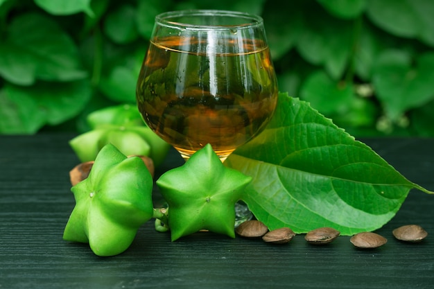 Photo sacha inchi, fresh capsule seeds fruit of sacha-inchi peanut with  tea on green leaf background