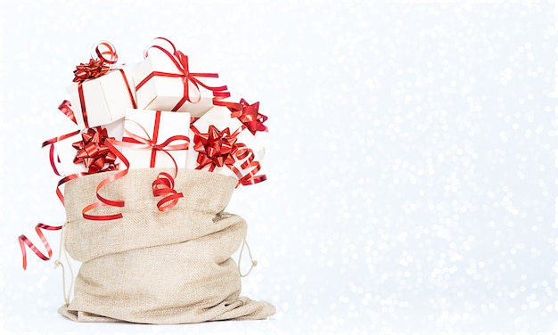 Фото Мешок приносит рождественские подарки подарочные пакеты с красным бантом на белом фоне