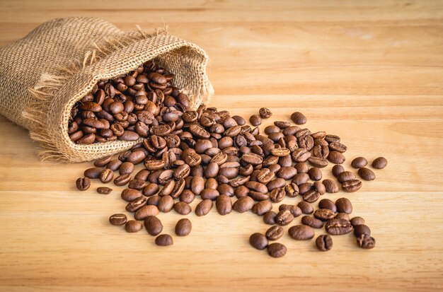 Sack of coffee beans on wooden background