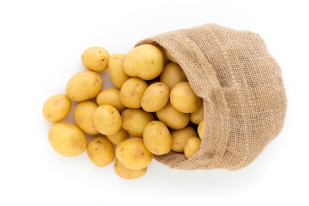 Sack of fresh raw potatoes on wooden, top view