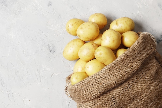 Sacco pieno di patate novelle su sfondo grigio con posto per il testo