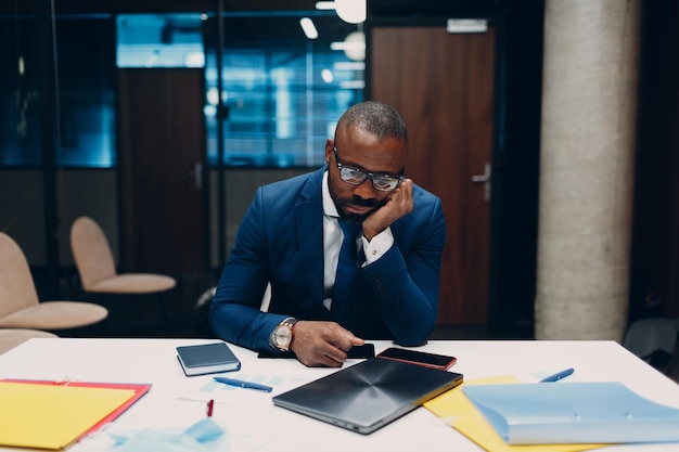 Sad african american black Businessman sit at office table. Business people in crisis and depression after covid-19 pandemia concept.