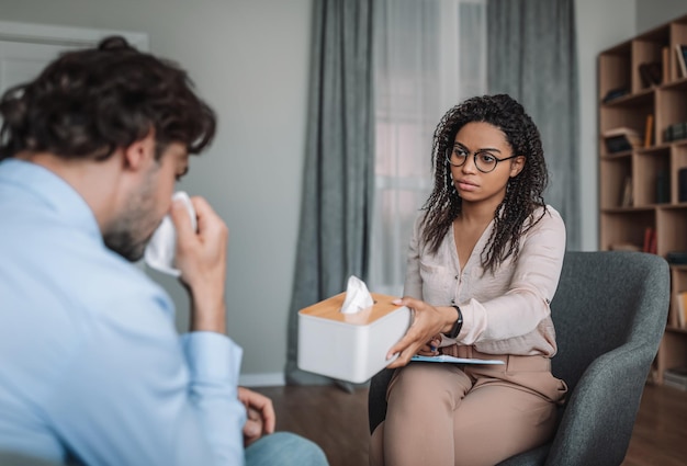 Sad african american millennial woman doctor calming crying european man