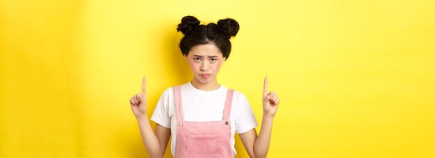 写真 悲しそうで悲しそうなアジア人女性 眉をひそめて 指を挙げて 不公平な立場について 文句を言う