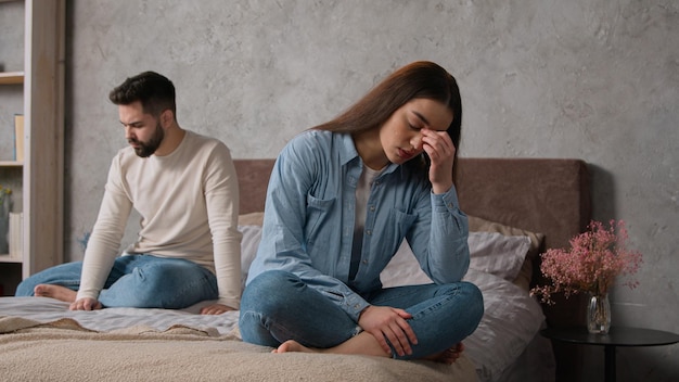 Sad annoyed caucasian couple family spouses sit apart on bed offended man and woman relationship