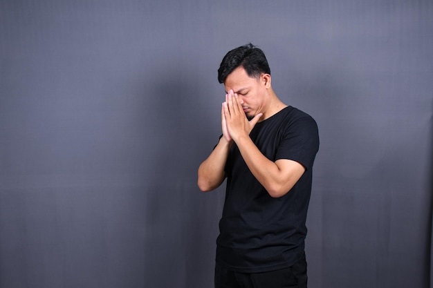 sad asian man with hands on face in sadness, isolated on gray background, copyspace