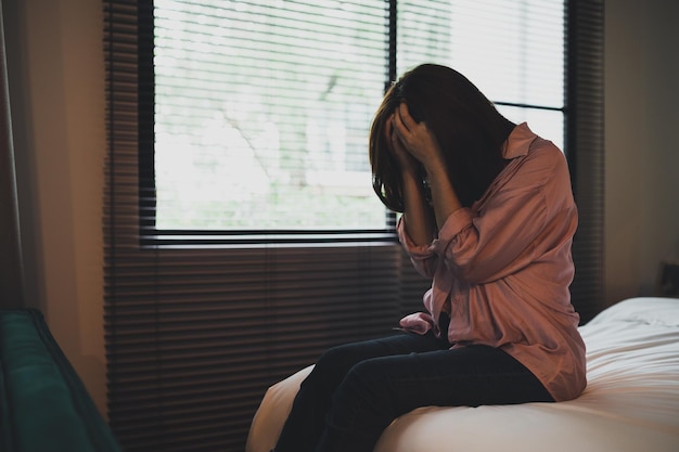 Sad asian woman suffering depression insomnia awake and sit\
alone on the bed in bedroom sexual harassment and violence against\
women health concept