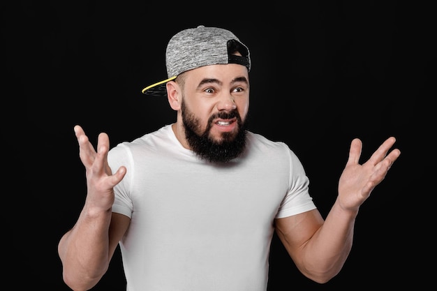 Sad bearded football fan in cap screaming on black background. man watching sports and supporting team