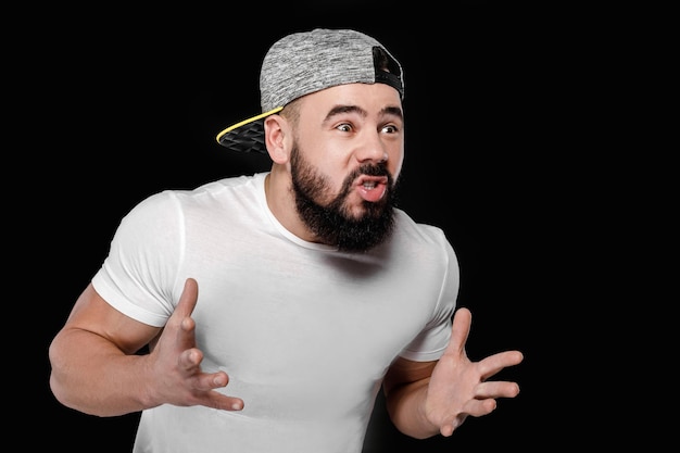 Sad bearded football fan in cap screaming on black background. man watching sports and supporting team