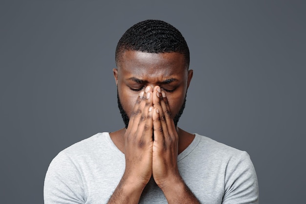sad black man holding his nose because sinus pain
