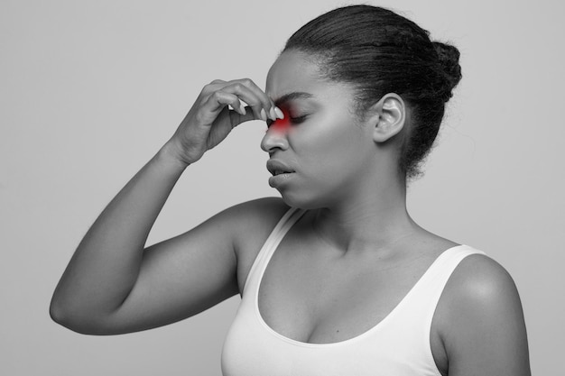 Sad black woman holding her nose because sinus pain
