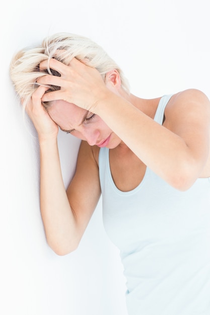 Sad blonde woman with head pain holding her head 