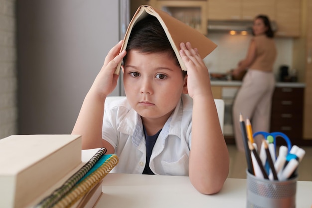 本で頭を覆う悲しい少年