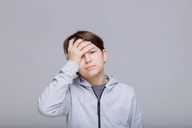 Il ragazzo triste si tiene la testa adolescente che si sente male con mal di testa