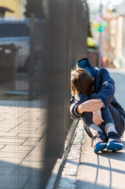 sad boy sitting and crying on street
