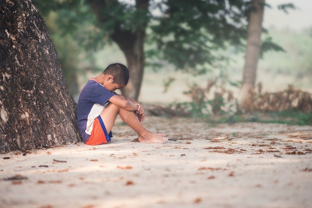 A Sad boy sitting with tree