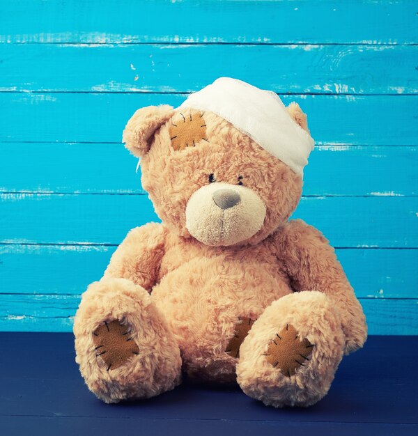 Sad brown bear sits with bandaged white medical bandage head