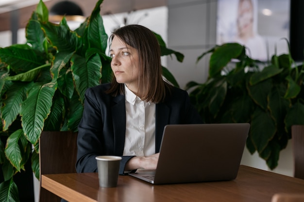 Sad business woman with dark short hair working at the computer and bored