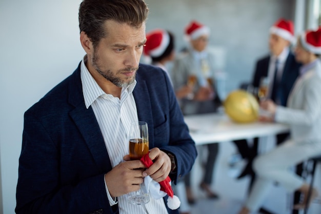 Sad businessman feeling left out from his colleagues during\
christmas party in the office