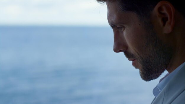Foto uomo d'affari triste guardando la finestra panoramica con vista sul mare ritratto dello specialista del leader
