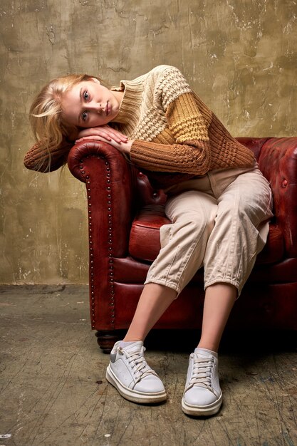 sad caucasian woman sits in contemplation on leather couch sofa