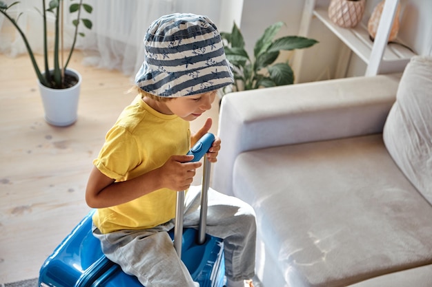 A sad child sits on a suitcase and waits for departure family relocation flight from the country