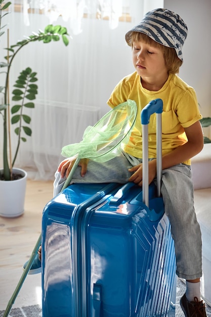 A sad child sits on a suitcase and waits for departure family relocation flight from the country