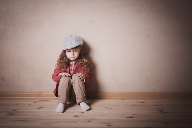 Sad child sitting on the floor in room