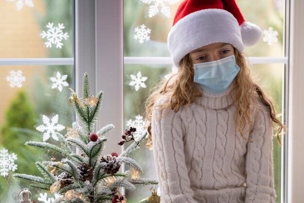 Sad child stay at home in Christmas time. Winter holiday during pandemic coronavirus COVID 19 concept