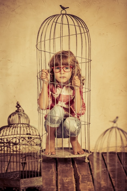 Sad child in steel cage. Human rights concept