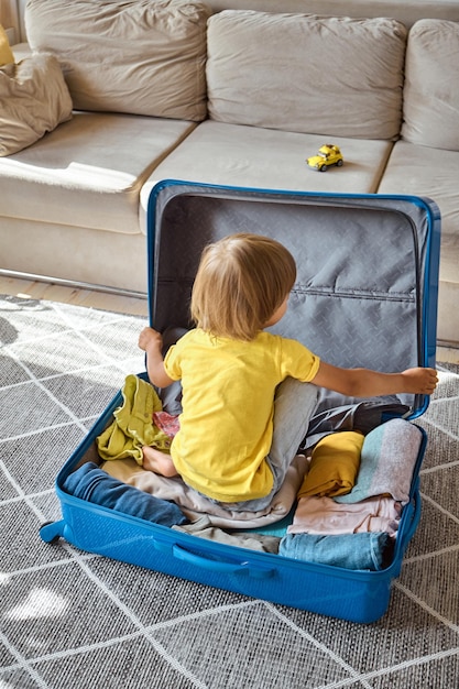 A sad child in a suitcase is waiting for departure family relocation flight from the country