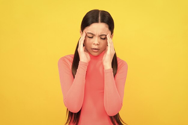 Photo sad child with headache on yellow background stress