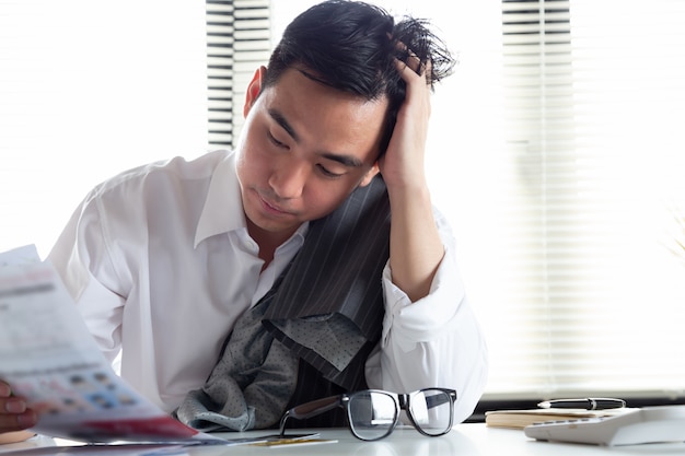 Sad confused and stressed of young Asian man holding bills letter of credit card debt, Financial money problem and tax invoice notification concept