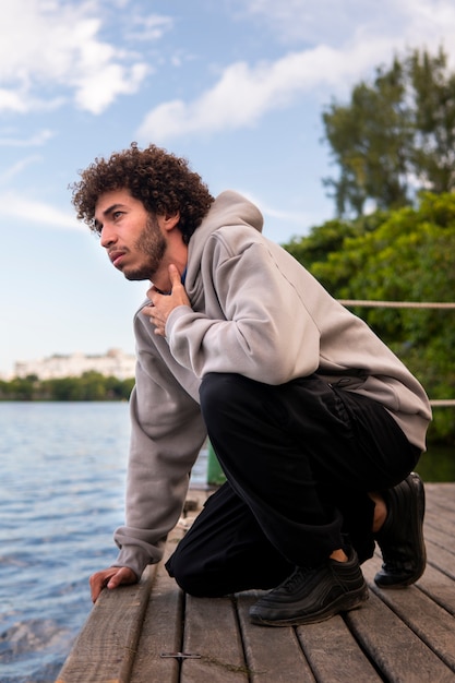 Foto uomo triste e contemplativo seduto in riva al lago