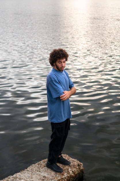 Foto uomo triste e contemplativo seduto in riva al lago