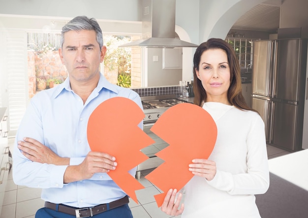 Sad couple holding broken hearts at home