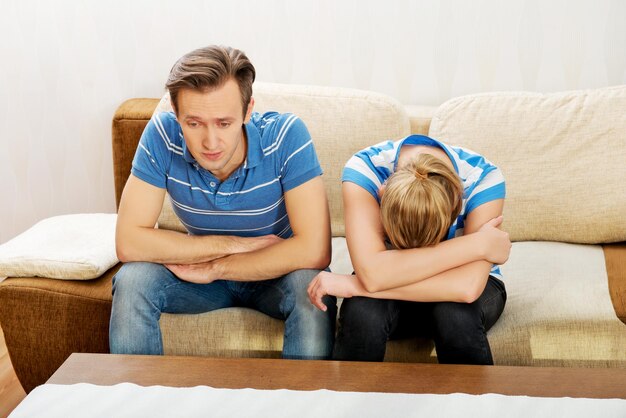 Photo sad couple sitting on sofa at home