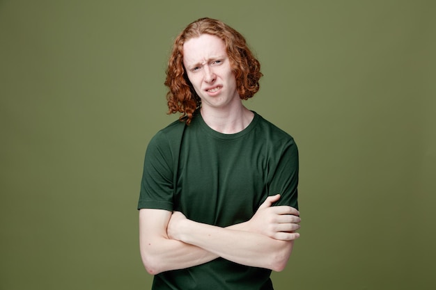 Sad crossing hands young handsome guy wearing green t shirt isolated on green background