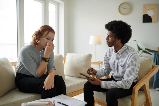sad crying young woman talking to therapist about her traumatic experience