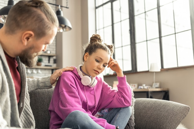 可哀想な娘。ピンクのスウェットシャツを着た10代の娘が、学校での問題の後に悲しむ