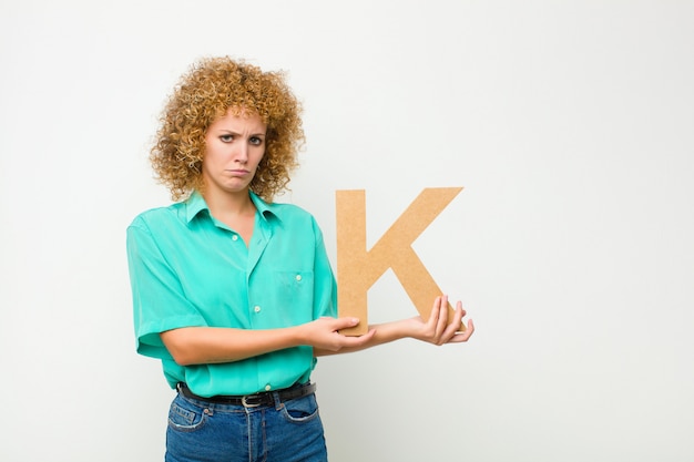 sad, depressed, unhappy, holding the letter K of the alphabet to form a word or a sentence.